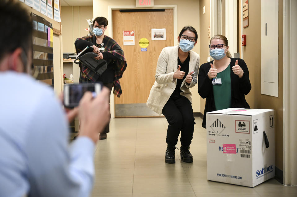 From right, Hayley Kytta and Tam Nguyen, both 4th year pharmacy students at the University of Minnesota, pose for a photo with a box containing 975 doses of the Pfizer-BioNTech vaccine for COVID-19 which just arrived at North Memorial Health Hospital Tuesday, Dec. 15, 2020 in Robbinsdale, Minn. (Aaron Lavinsky/Star Tribune via AP, Pool)