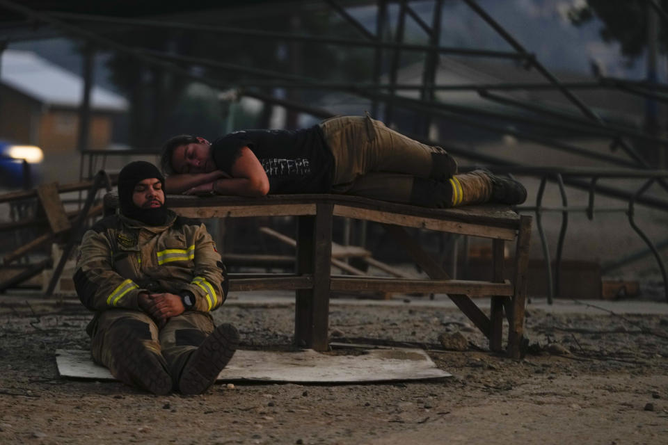 Firefighters take a break after fighting the flames of a forest fire reaching Vina del Mar, Chile, Saturday, Feb. 3, 2024. (AP Photo/ Esteban Felix)