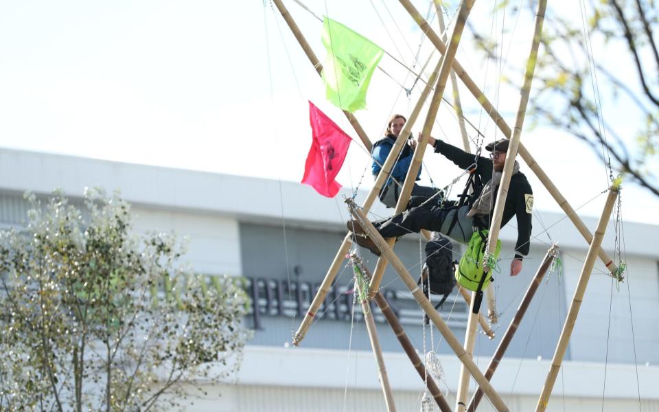 Two protesters use bamboo lock-ons to block the road outside the Newsprinters printing works at Broxbourne, Hertfordshire - Yui Mok/PA