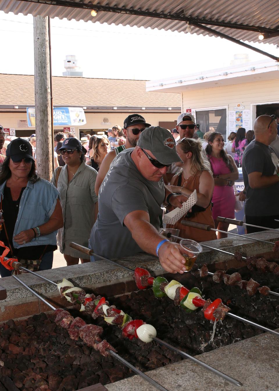 David Day seasoning his skewer of carne d'espeto and veggies at the 107th Feast of the Blessed Sacrament on Sunday, August 6, 2023, at the Madeira Feast grounds in New Bedford.