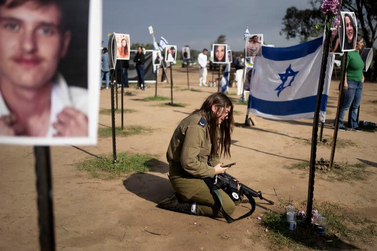 Una soldado israelí llora junto a un cartel que recuerda a una persona secuestrada el 7 de octubre en el ataque transfronterizo de Hamas contra el festival de música Nova, tras una conferencia de prensa en Re'im, en el sur de Israel, el 5 de enero de 2024.