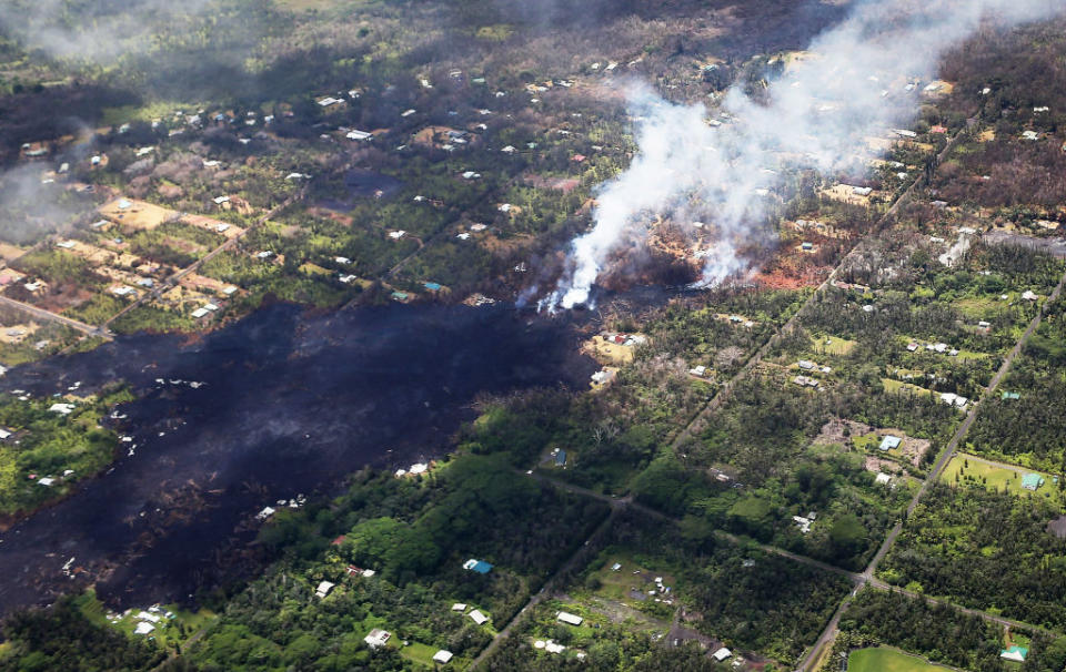 <p>Smoke and volcanic gases rise as lava (left centre) cools in the Leilani Estates neighborhood, in the aftermath of eruptions and lava flows from the Kilauea volcano on Hawaii’s Big Island, on May 11, 2018 in Pahoa, Hawaii. The U.S. Geological Survey said a recent lowering of the lava lake at the volcano’s Halemaumau crater Ãhas raised the potential for explosive eruptionsÃ at the volcano. Vog, a haze or smog containing gases, smoke and dust from volcanic eruptions, may eventually spread from the eruptions to other islands in Hawaii. (Photo from Mario Tama/Getty Images) </p>