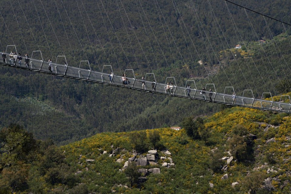 People walk across a narrow footbridge suspended across a river canyon, which claims to be the world's longest pedestrian bridge, in Arouca, northern Portugal, Sunday, May 2, 2021. The Arouca Bridge inaugurated Sunday, offers a half-kilometer (almost 1,700-foot) walk across its span, some 175 meters (574 feet) above the River Paiva. (AP Photo/Sergio Azenha)