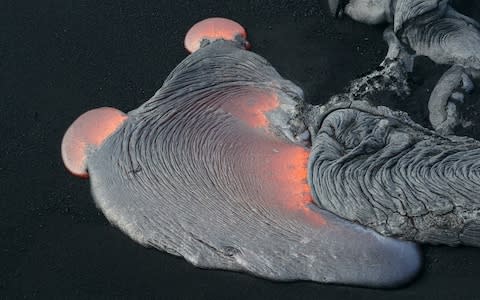Hot lava begins to solidify as it enters the ocean in Hawaii - Credit: Getty