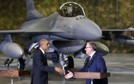 With an F-16 fighter in the background, U.S. President Barack Obama and Poland's President Bronislaw Komorowski (R) shake hands upon Obama's arrival at Chopin Airport in Warsaw June 3, 2014. REUTERS/Kevin Lamarque