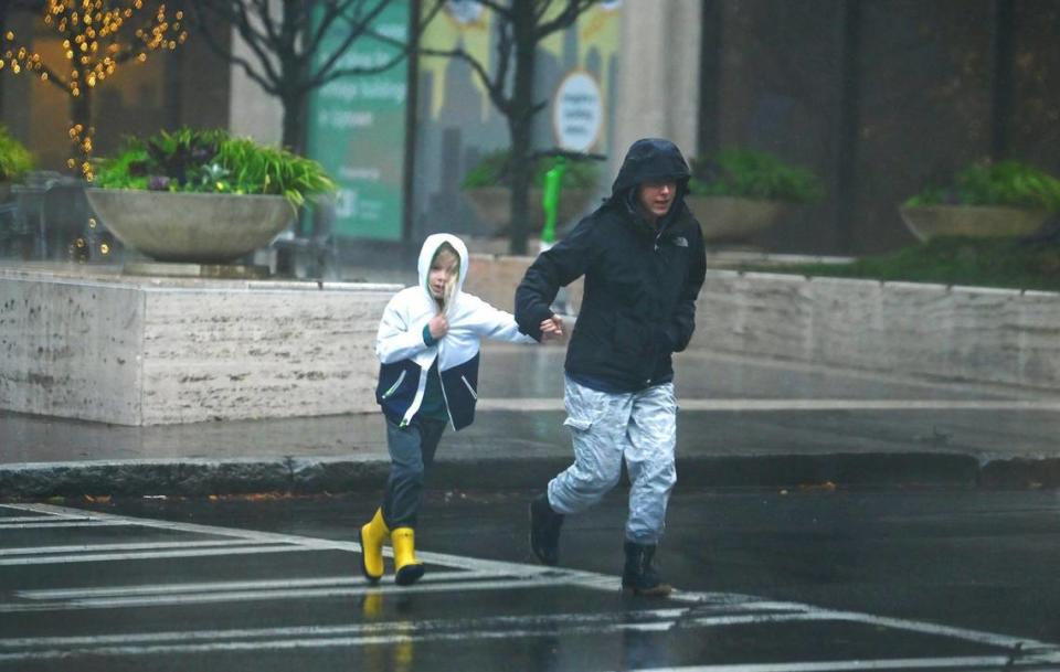 Pedestrians brace themselves against the rain and wind as they walk along South Tryon St. in Charlotte, NC on Tuesday, January 9, 2024.