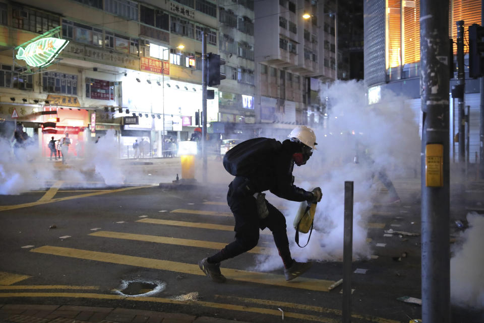 A demonstrator reacts as police fire tear gas during a protest in Hong Kong, Saturday, Nov. 2, 2019. Pro-democracy protesters attacked the office of Chinese news agency Xinhua for the first time Saturday, after familiar chaos downtown that saw police and demonstrators trading petrol bombs, tear gas and water cannon in the 22nd straight weekend of unrest. (AP Photo/Kin Cheung)