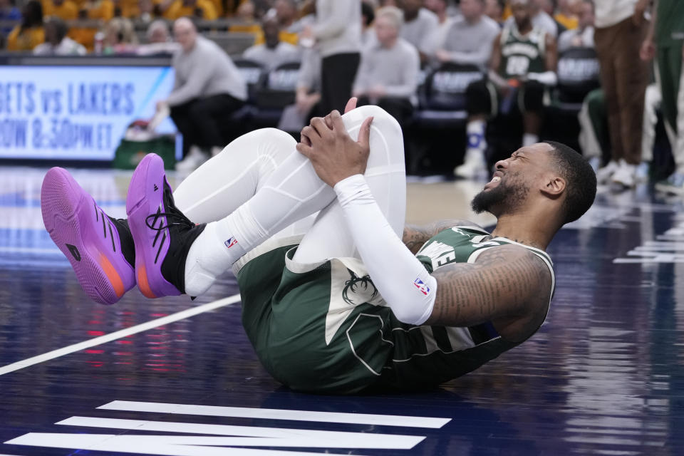 Milwaukee Bucks guard Damian Lillard (0) grabs his leg after being injured during the first half in Game 2 against the Indiana Pacers in an NBA basketball first-round playoff series, Friday, April 26, 2024, in Indianapolis. (AP Photo/Michael Conroy)