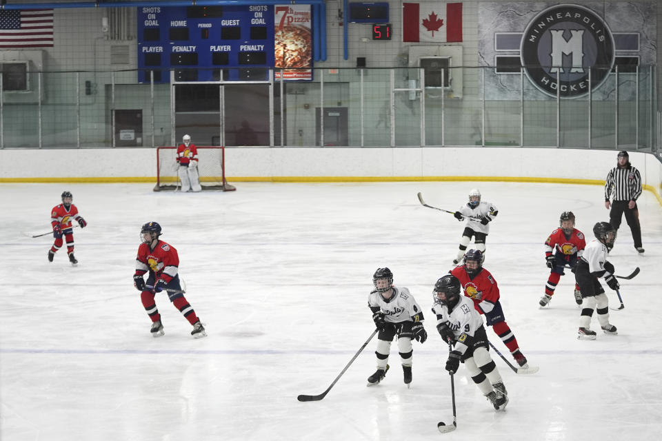 CORRECTS SPELLING FROM ORNO TO ORONO -Players on the Minneapolis, white and black uniforms, and Orono, red uniforms, teams compete in a 10-and-under youth hockey game Feb. 4, 2024, in Minneapolis. (AP Photo/Abbie Parr)