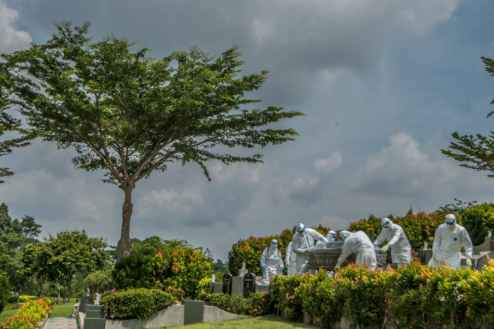 Workers in PPE suits carry the body of a person who died from the coronavirus disease (Covid-19) at a Christian cemetery in Semenyih, Selangor. — Picture by Shafwan Zaidon