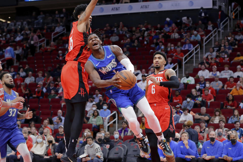 Minnesota Timberwolves forward Anthony Edwards, center, shoots in front of Houston Rockets center Christian Wood, left, and forward Kenyon Martin Jr. (6) during the first half of an NBA basketball game Sunday, Jan. 9, 2022, in Houston. (AP Photo/Michael Wyke)