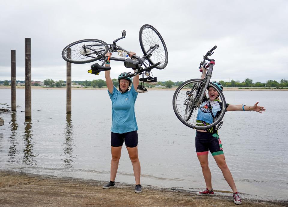 Cyclists Rosemary Washnok, left, of Brandon, South Dakota, and Lily Silverstein of Los Angeles celebrate after dipping their tires in the Mississippi River in Davenport to mark the end of their ride Saturday.