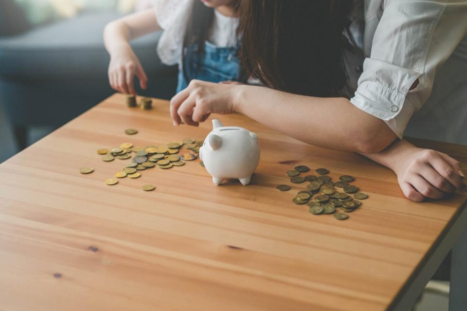 An image of a mother and her daughter counting coins from a piggy bank.