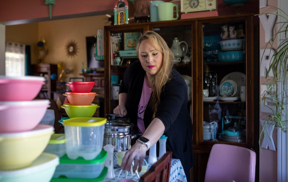 Janet Henriksen Lloyd, a Tupperware consultant and stay-at-home mother of four, arranges the Tupperware on her kitchen table in Davison on Friday, May 26, 2023. 