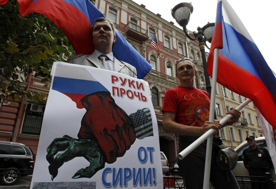 Participants hold a placard and wave a flag during a protest against possible U.S. military action in Syria near the U.S. consulate in St. Petersburg