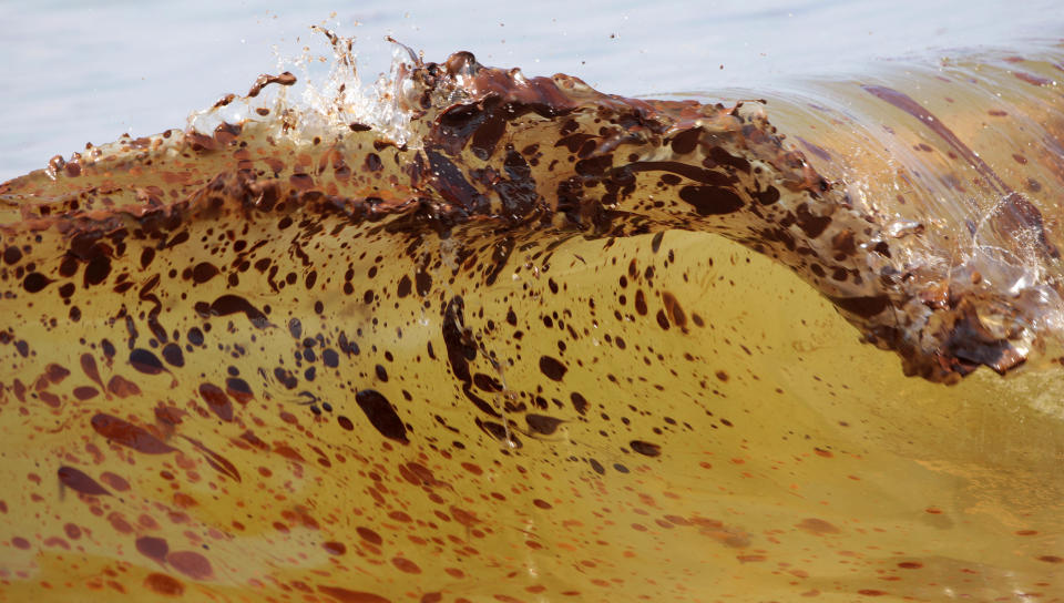 FILE - In this Saturday, June 12, 2010 file photo taken by Dave Martin, crude oil from the BP Deepwater Horizon spill is seen inside a wave as it washes ashore in Orange Beach, Ala. Martin, a longtime Associated Press photographer based in Montgomery, Ala., died after collapsing on the Georgia Dome field at the Chick-fil-A Bowl on Tuesday, Dec. 31, 2013. Martin was 59. (AP Photo/Dave Martin, File )