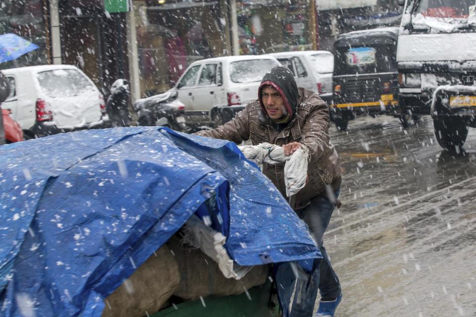 A Kashmiri man pushes a cart carrying goods as it snows in Srinagar, Indian controlled Kashmir, Saturday, Jan. 28, 2017. Authorities in Indian-controlled Kashmir have issued avalanche warnings for many parts of the region, as the heavy snowfall has cut off roads, disrupted power and communication lines, and forced the evacuation of hundreds of residents. (AP Photo/Dar Yasin)