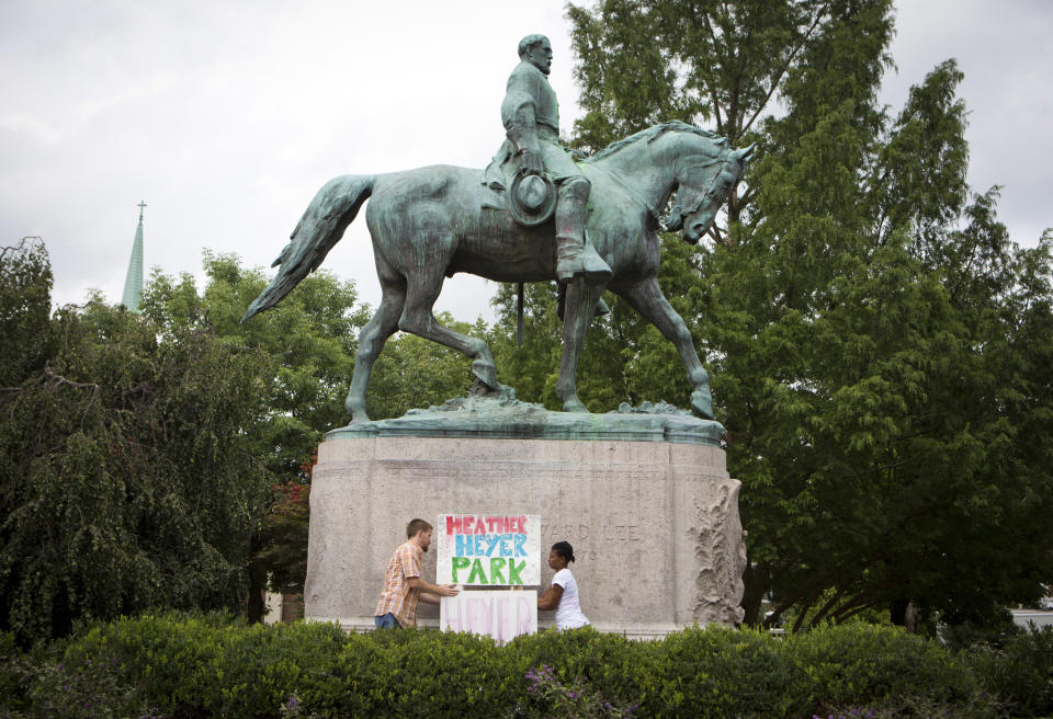 <p>Tom Lever, 28, and Aaliyah Jones, 38, both of Charlottesville, put up a sign that says “Heather Heyer Park” at the base of the Confederate general Robert E. Lee monument in Emancipation Park Tuesday, Aug. 15 in Charlottesville, Va. Alex Fields Jr., is charged with second-degree murder and other counts after authorities say he rammed his car into a crowd of counterprotesters, including Heyer, Saturday, where a white supremacist rally took place. (Photo: Julia Rendleman/AP) </p>