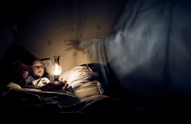 Child in bed looking at a glowing lantern, with a figure's outstretched hand