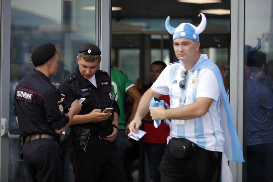 FILE - In this June 17, 2018, file photo, a soccer fan walks past two Russian police officers as they control an entrance ahead of the group F match between Germany and Mexico at the 2018 soccer World Cup in the Luzhniki Stadium in Moscow, Russia. A year after hosting the World Cup, Russia is boasting the biggest club soccer crowds since Soviet days and participation at the amateur level is on the rise. Still, there are signs of trouble for the sport. (AP Photo/Alexander Zemlianichenko, File)