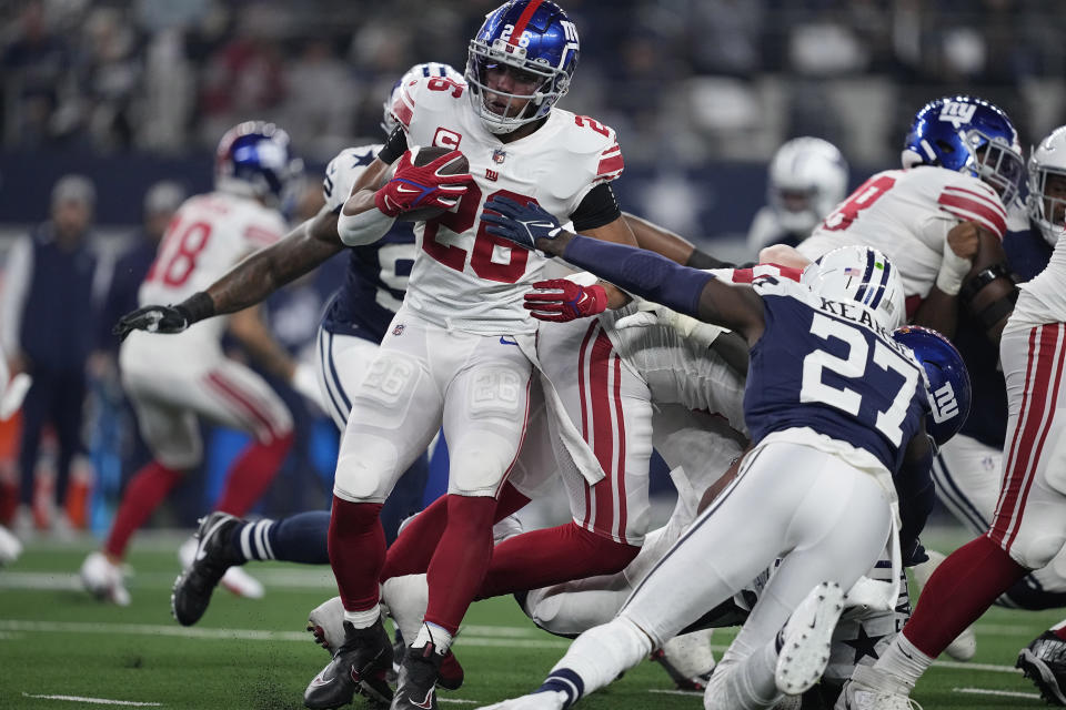 New York Giants running back Saquon Barkley (26) is stopped by Dallas Cowboys safety Jayron Kearse (27) during the first half of an NFL football game Thursday, Nov. 24, 2022, in Arlington, Texas. (AP Photo/Tony Gutierrez)