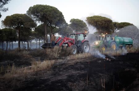 A man rides on a tractor while helping to put out a forest fire near Donana National Park in Mazagon, southern Spain June 25, 2017. REUTERS/Jon Nazca