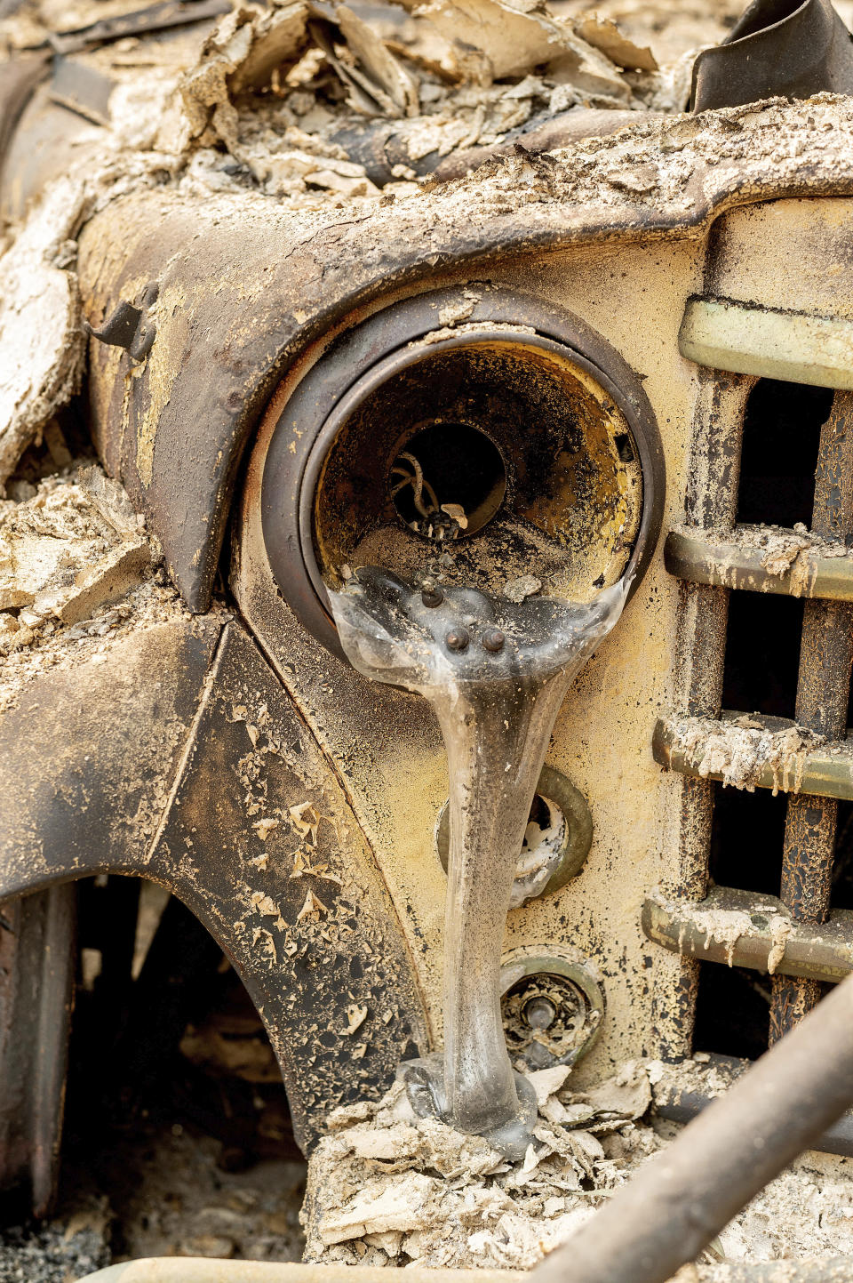 Melted glass falls hangs from the headlight of a 1951 Willys-Overland Jeepster destroyed by the LNU Lightning Complex fires in Vacaville, Calif., on Friday, Aug. 21, 2020. (AP Photo/Noah Berger)