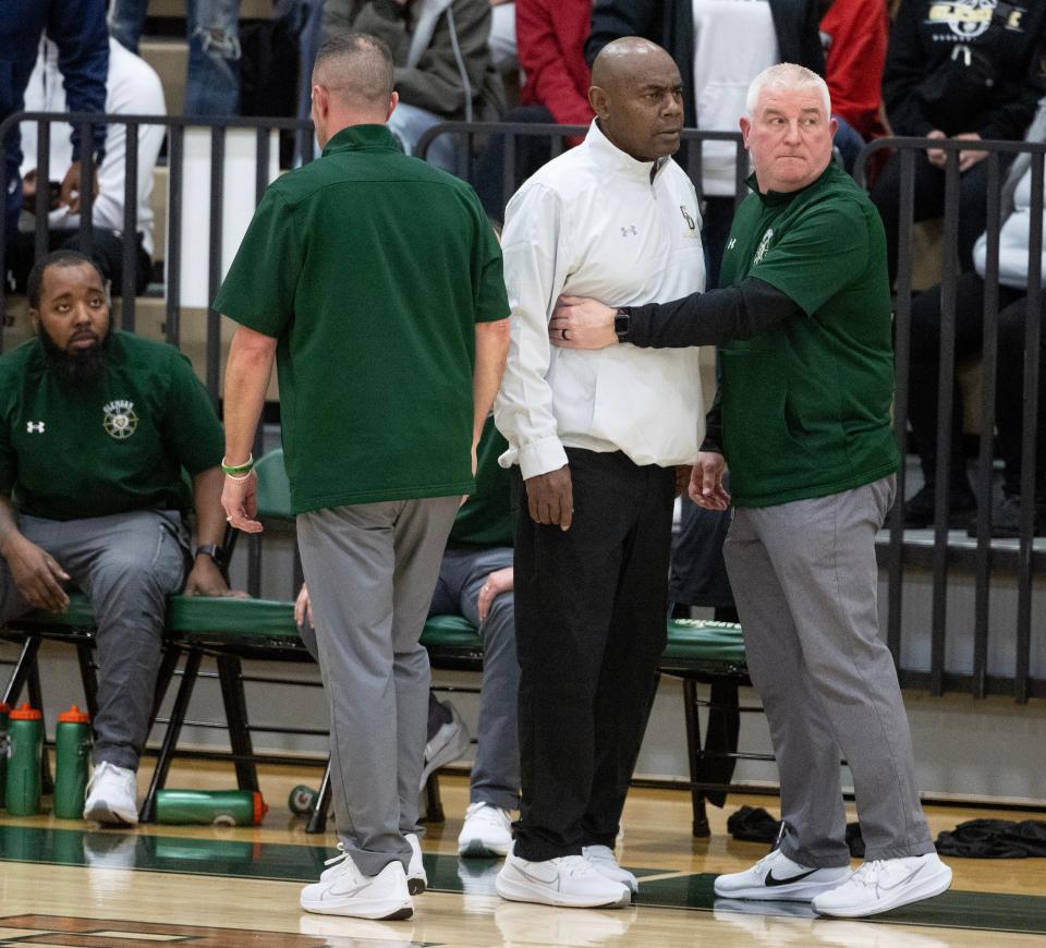 GlenOak varsity basketball coach Rick Hairston is held back by his assistant coaches after a technical in the fourth quarter against Green Tuesday, January 9, 2024.