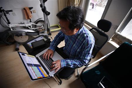 Chinese cartoonist Wang Liming uses his computer inside his apartment before an interview with Reuters in Beijing, Ocotober 22, 2013. REUTERS/Petar Kujundzic