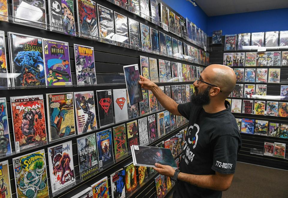 Julian De La Torre, owner of Sky High Comics & Games, organizes the shelves of comic books on display inside the business on the east side of the outlet mall on Friday, March 15, 2024, in Fort Pierce. 'We've been here since April of last year,' De La Torre said. 'Looking forward to other stores here, other anchor stores to support us, so we could all support each other, because right now we feel like the lone wolf out here.'