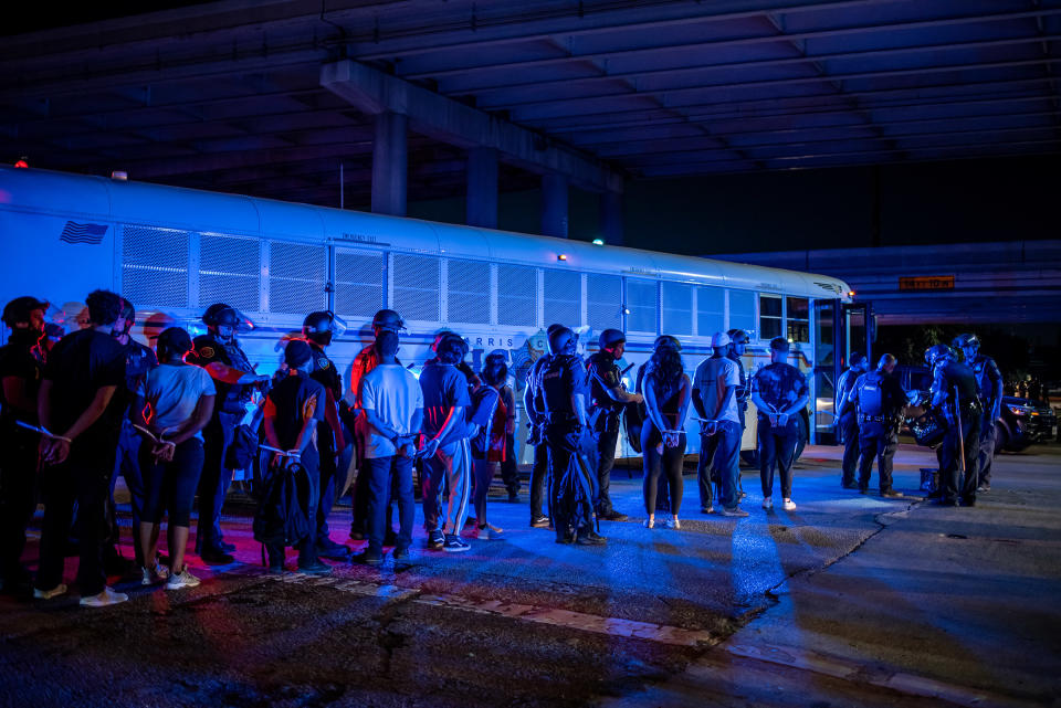 A group of people being placed under arrest stand by a Harris County Jail bus in Houston on June 2, 2020.<span class="copyright">Sergio Flores—Getty Images</span>