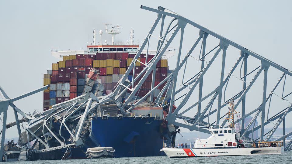 A Coast Guard cutter passes a cargo ship that is stuck under the part of the structure of the Francis Scott Key Bridge after the ship his the bridge Tuesday, March 26, 2024, in Baltimore, Maryland. - Steve Helber/AP