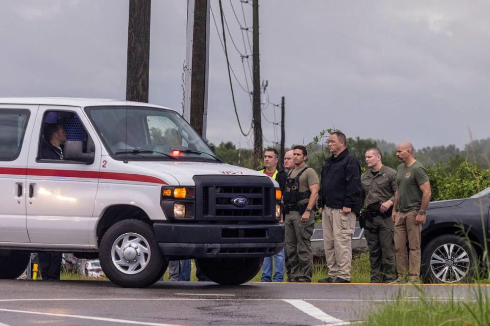 Law enforcement officers, watch as a procession leaves the scene where a deputy was shot and killed in eastern Wake County near the intersection of Auburn Knightdale and Battle Bridge Roads Friday, Aug. 12, 2022.