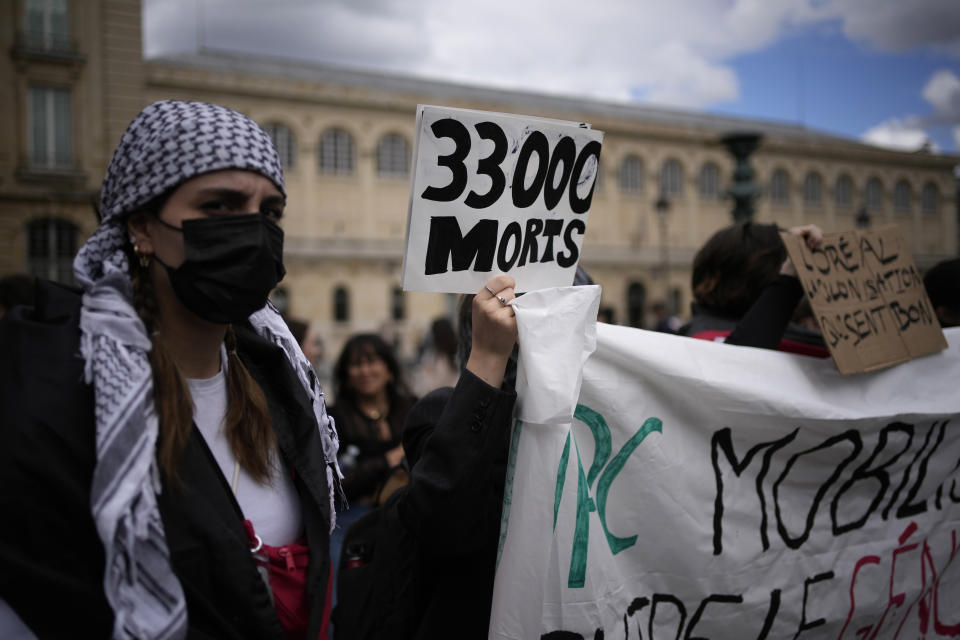 A student holds a poster reading "33 000 dead" during protest near the Pantheon monument Friday, May 3, 2024 in Paris. Students waved Palestinian flags and chanted slogans in support of residents of Gaza, as Israel continues its offensive following the deadly Oct. 7 Hamas-led attack that triggered the Israeli-Hamas war. (AP Photo/Christophe Ena)