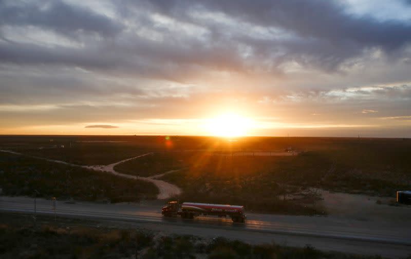 FILE PHOTO: The sun rises behind an oil tanker driving through the Permian Basin in Mentone