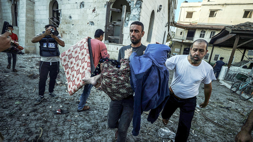 An injured Palestinian is carried away from Al-Ahli Baptist Hospital after it was hit in Gaza City, Gaza on October 18, 2023.