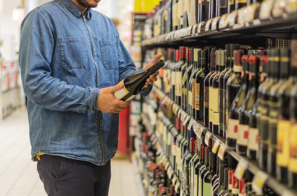 Man is buying a bottle of wine at the supermarket. ; Shutterstock ID 491848462; Cost Ctr: redownload; Manager: redownload; Email: redownload; Project: redownload