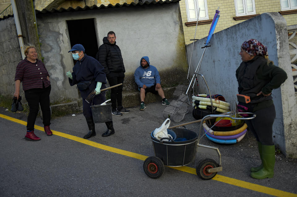 Clam diggers prepare their working tools before starting their work day in the estuary of Lourizan, in Galicia, northern Spain, Tuesday, April 18, 2023. They fan out in groups, mostly women, plodding in rain boots across the soggy wet sands of the inlet, making the most of the low tide. These are the clam diggers, or as they call themselves, "the peasant farmers of the sea." (AP Photo/Alvaro Barrientos)