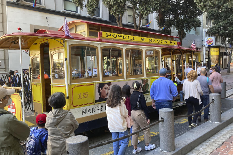 People line up to board a cable car at the Powell Street turnaround plaza in San Francisco on Monday, Aug. 2, 2021. San Francisco's iconic cable cars are rolling again after being sidelined by the pandemic for months. People were already forming long lines to ride the cable cars, which will offer free rides the month of August. (AP Photo/Olga Rodriguez)