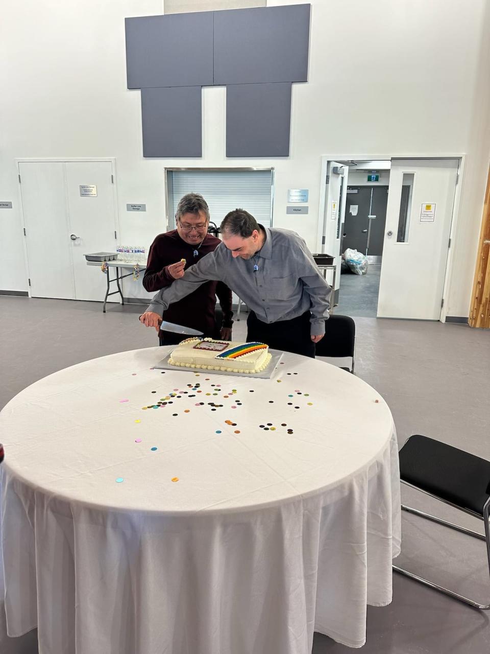 Mark Moberly, left, and Russell Salfi cut into their wedding cake. The wedding was organized by the community during 2SLGBTQ+ celebrations.