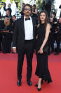 Des souliers noirs vernis (une tendance remarquée tout au long du Festival) pour Vincent Elbaz et une robe à encolure américaine et léger volant pour la journaliste Fanny Conquy. Le couple s’est présenté en mode dark sur le red carpet de la cérémonie de clôture.