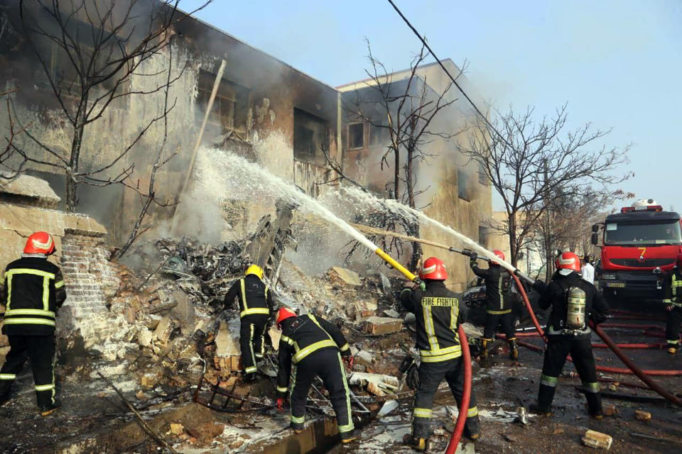 In this photo released by Tasnim News Agency, firefighters extinguish a fire at the scene of a crash of an F-5 fighter jet that killed two pilots and a civilian, in Tabriz, northwestern Iran, Monday, Feb. 21, 2022. Gen. Reza Yousefi, commander of the air base in Tabriz, said the crashed jet had been used for training and suffered a technical problem on its final flight. (Tasnim News agency via AP)