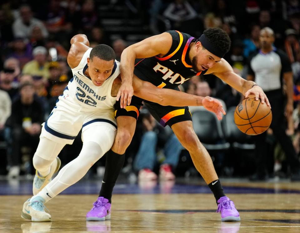 Grizzlies guard Desmond Bane (22) goes for the steal on Suns guard Devin Booker (1) during a game at the Footprint Center in Phoenix on Dec. 2, 2023.
