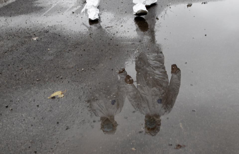 Doctor Luigi Cavanna, right, and his nurse assistant Gabriele Cremona are reflected in a puddle after doing a house call on a COVID-19 patient, in Travo, near Piacenza, Italy, Wednesday, Dec. 2, 2020. (AP Photo/Antonio Calanni)