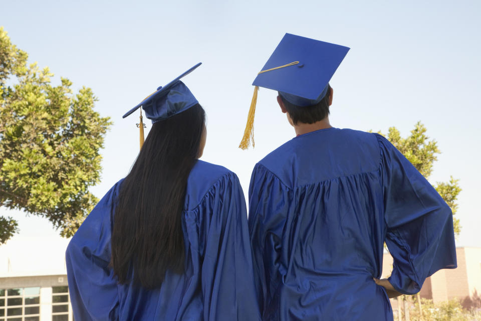 Two graduates in caps and gowns facing away, symbolizing academic achievement