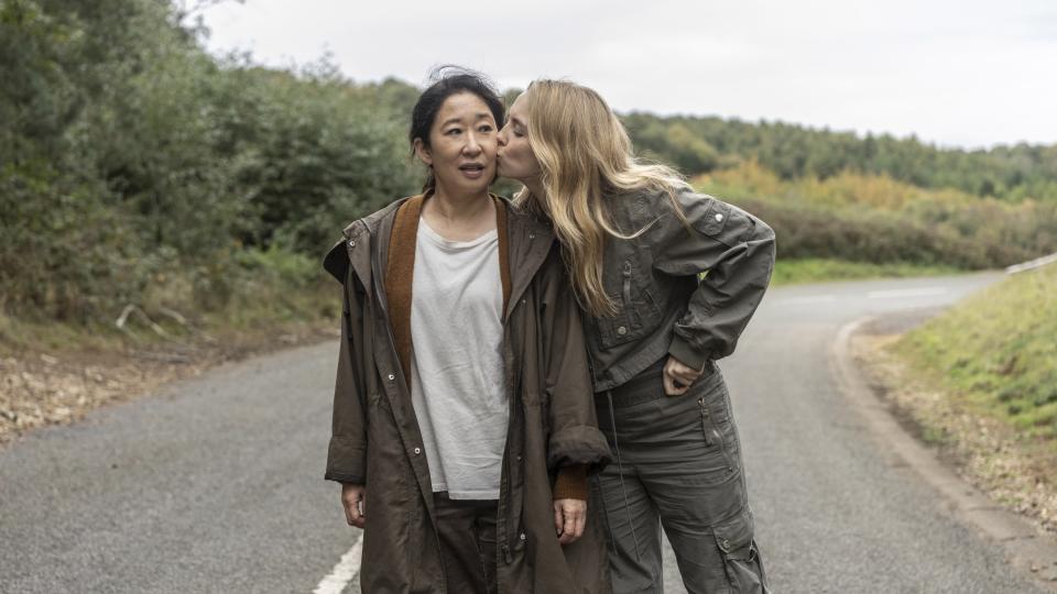 woman kissing another woman on the cheek as they walk in the middle of the road