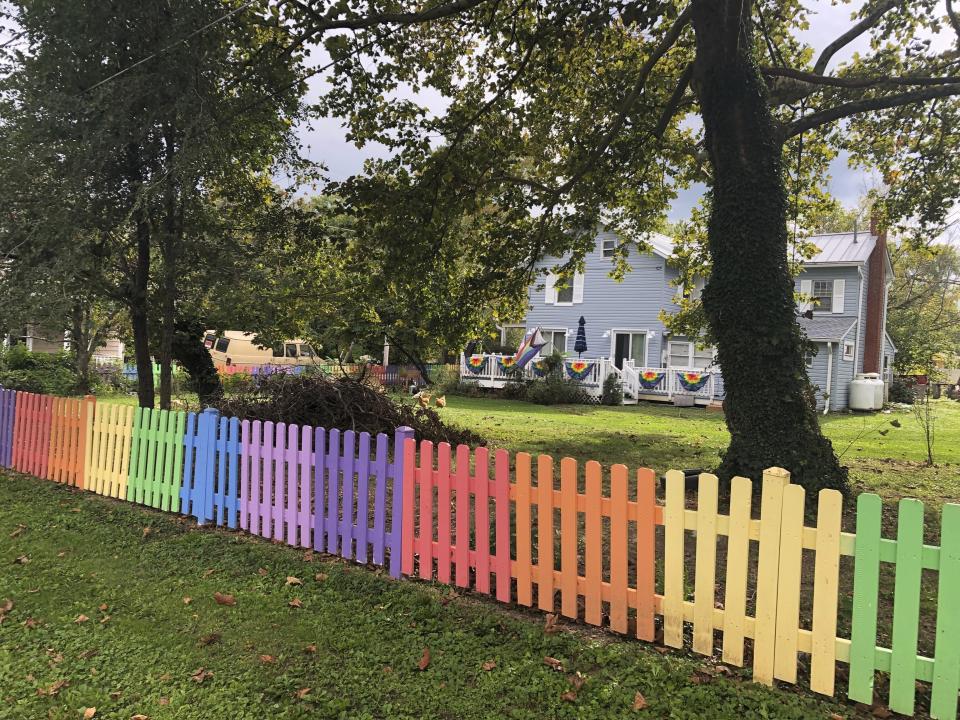 A home along Pennsylvania Avenue, in Lovettsville, Va., displays a fence painted in the colors of the gay-pride rainbow flag, on Oct. 4, 2021. About 20 neighbors showed up to help the owners, Kris Consaul and Sheryl Frye, when they decided on the paint scheme in 2020 as a way to support the town's LGBT youth when young people were isolated at home in the pandemic. The fence has become a showpiece, delighting many neighbors. But in the 2020 campaign, a pro-Trump parade of vehicles diverted off the main street to blast car horns at their property. (AP Photo/Cal Woodward)