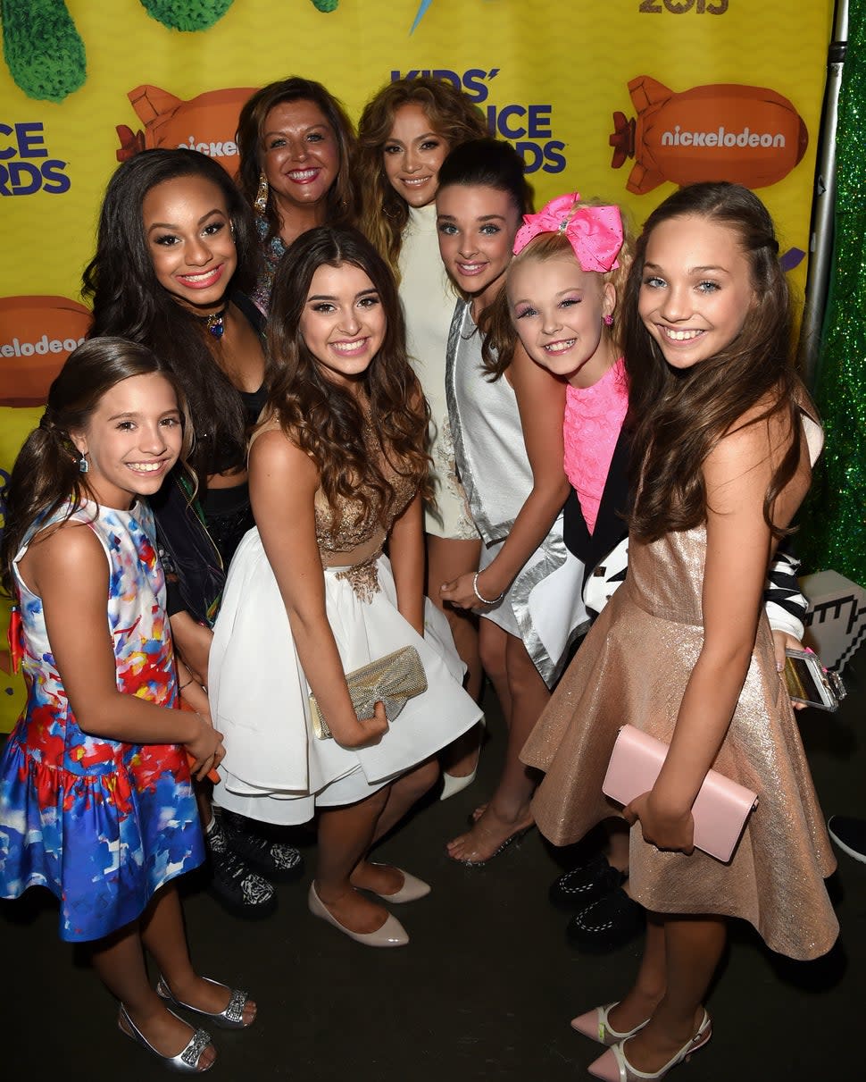 Jennifer Lopez poses with tv personality Abby Lee Miller and dancers Mackenzie Ziegler, Nia Sioux Frazier, Kalani Hilliker, Kendall Vertes, Chloe Lukasiak and Maddie Ziegler from the show Dance Moms backstage at Nickelodeon's 28th Annual Kids' Choice Awards held at The Forum on March 28, 2015 in Inglewood, California.