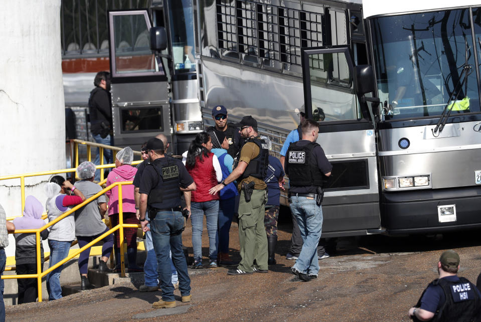 Las trabajadoras esposadas son escoltadas a un autobús para ser transportadas a un centro de procesamiento luego de una redada de funcionarios de inmigración estadounidenses en una planta de Koch Foods, en Morton, Miss. (Foto AP / Rogelio V. Solis)