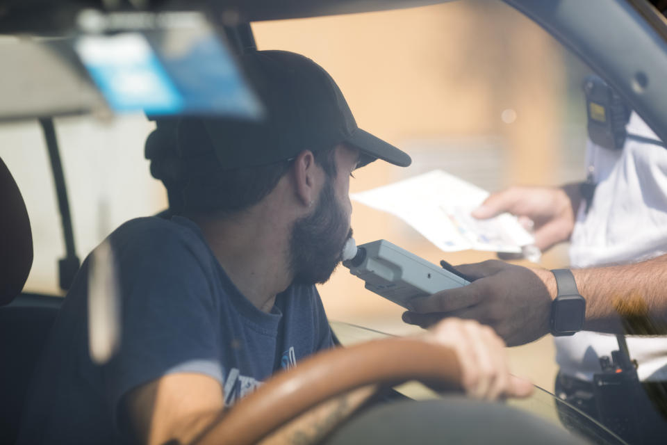 Highway 2 Bucharest - Constanta, Romania - 10 August, 2021: Romanian Road Police officer hands a breathalyser to a driver to test his alcohol level.